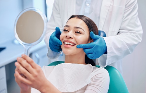 girl sitting in dentist chair looking in mirror